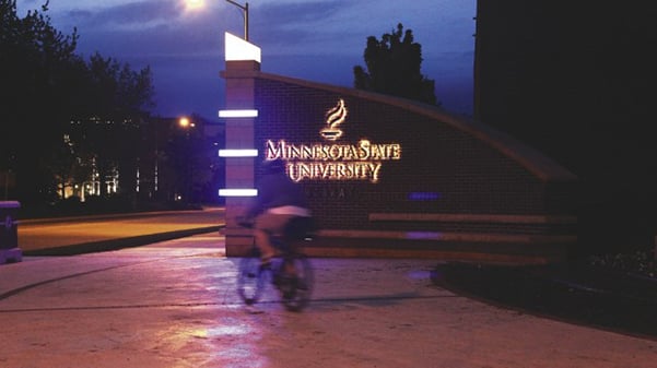 a person riding a bike in front of a sign