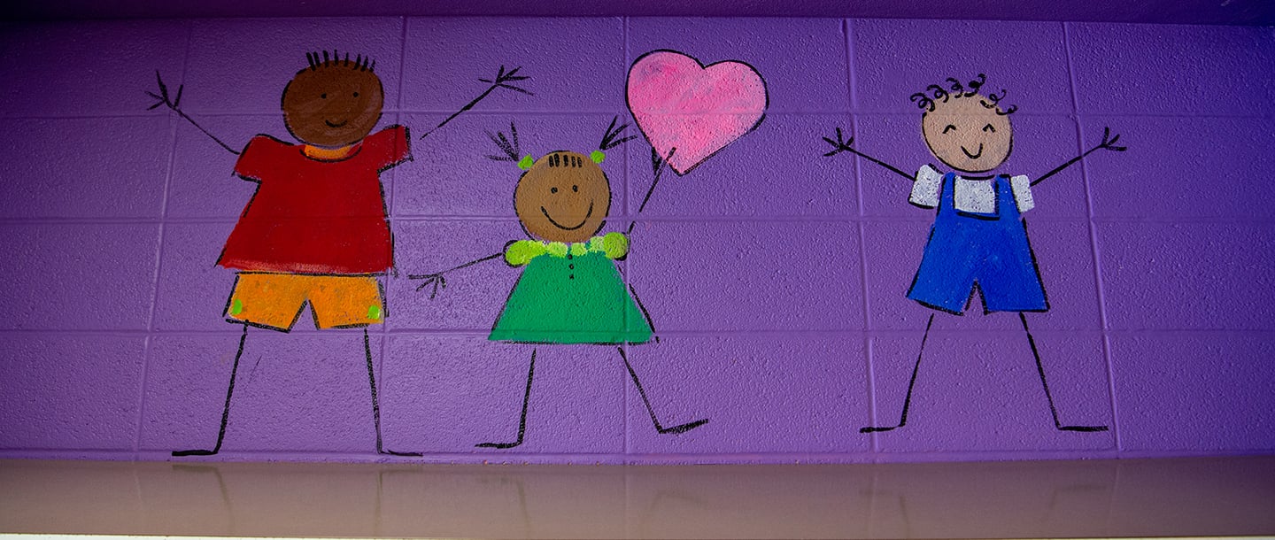 a wall with drawings of kids holding a heart and a couple of children