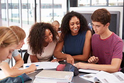 Teacher talking to students at a table.